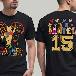 May include: Black t-shirt featuring a colorful Disney design with Winnie the Pooh, fireworks, and the text "Disney Trip 2-26" on the front. The back displays "DANIEL 15" with Disney characters.