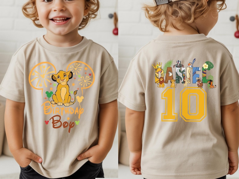 Puede incluir: Camiseta beige de manga corta con un gr&aacute;fico de Simba y el texto "Birthday Boy" en la parte delantera. La parte trasera de la camiseta tiene el nombre "Daniel" y el n&uacute;mero "10" en amarillo.