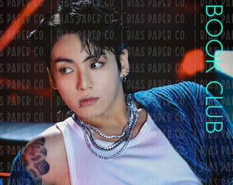 May include: A promotional image featuring a person with tattoos, piercings, and jewelry, wearing a white tank top and a blue patterned jacket. The image has text that reads "GOOD GIRL BOOK CLUB" in pink and teal.