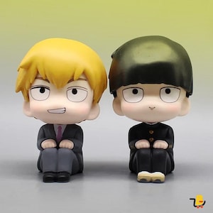 Puede incluir: Dos figuras de estilo anime. Una tiene el pelo amarillo, un traje negro y una corbata morada. La otra tiene el pelo negro y un uniforme negro. Ambos están sentados con las manos en las rodillas. El fondo es un degradado de amarillo y verde.