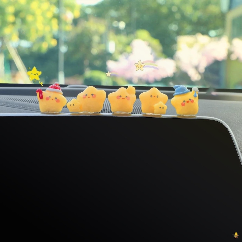 May include: A row of yellow star-shaped figurines with smiling faces and various small hats. The figurines are arranged on a dark surface, with a blurred background of green foliage and a bright sky.