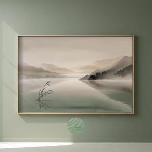 Può includere: Una stampa incorniciata di un paesaggio sereno con un lago e montagne nebbiose. L'opera d'arte presenta toni tenui e smorzati di verde, beige e grigio, creando un'atmosfera tranquilla. Alcune canne sono in primo piano.