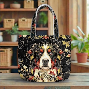 May include: Black tote bag with a Bernese Mountain Dog design, featuring red, gold, and white floral details. The bag has a black background with a floral pattern and the name "Jenny" in script.