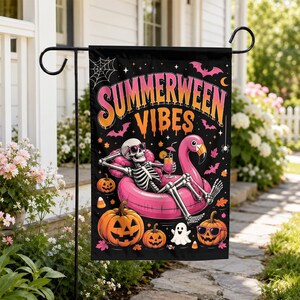 May include: A black garden flag featuring the text SUMMERWEEN VIBES in orange and pink. The design shows a skeleton wearing sunglasses, lounging in a pink flamingo pool float with a drink, surrounded by jack-o'-lanterns, bats, and a ghost.