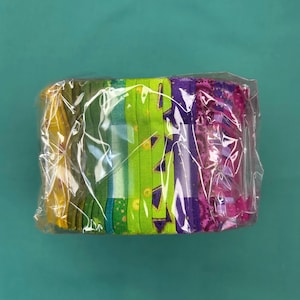 May include: A bundle of colourful fabric strips in a clear plastic package. The fabric features various patterns and colours, including yellow, green, purple, and pink. The strips are neatly stacked, ready for crafting or sewing projects.