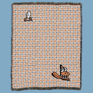 May include: A white and black grid throw blanket with a repeating pattern of orange smiley faces. The blanket features two cartoon characters: a walking cloud and a smiling alligator. The blanket has a fringed edge.