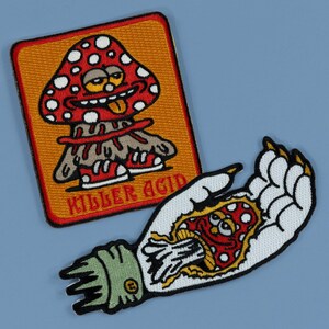 May include: Two embroidered patches. One features a red mushroom with white spots, a smiling face, and the text "KILLER ACID" on an orange background. The other shows a hand with a mushroom design inside.
