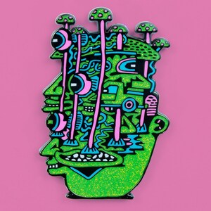 May include: Green and black enamel pin with a glittery green face and pink and blue mushrooms growing out of the top of the head.