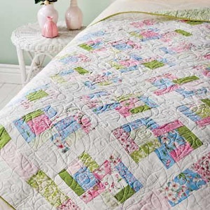 May include: A white quilt with a floral pattern in shades of pink, green, and blue. The quilt is quilted with a swirling pattern.