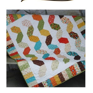 May include: A white crib quilt with a snake charmer design. The quilt features a patchwork of colorful fabrics with geometric shapes and a white background. The quilt is bordered with a colorful striped fabric.