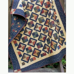 May include: A quilt pattern called "Diamond Dandy" by Little Louise Designs. The quilt is made with a charm square, layer cake, and fat quarter friendly pattern. The quilt is made with fabrics from Cattails & Clover by Kansas Troubles for Moda.