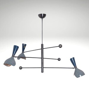 Op de afbeelding: Een moderne kroonluchter uit het midden van de eeuw met een donker bronzen afwerking. De armatuur heeft drie grijsblauwe, kegelvormige kappen met een bronzen binnenkant. De armen strekken zich horizontaal uit met bolvormige accenten.