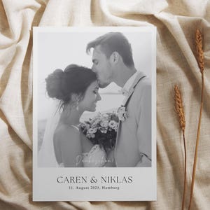 Könnte beinhalten: Schwarz-weiß Hochzeitsankündigung mit einem sich küssenden Paar, mit dem Text "Caren & Niklas" und dem Datum "11. August 2025, Hamburg". Die Ankündigung befindet sich auf weißem Hintergrund.