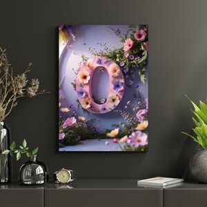 Op de afbeelding: Een ingelijste canvas print met de letter 'O' versierd met kleurrijke bloemen. De roze letter is versierd met bloemen en bladeren. De vage achtergrond creëert een fantasierijke tuinachtige sfeer. Het kunstwerk hangt aan een donkergrijze muur.