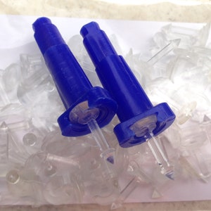 May include: Two blue plastic syringe-like tools with clear needles and a pile of clear plastic pieces.