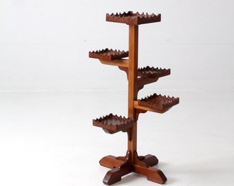 May include: A wooden plant stand with five shelves, each with a decorative edge. The stand is made of dark brown wood and has a tree-like design.