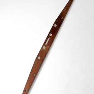 May include: A wooden level with metal brackets at each end. The level has several holes along its length.