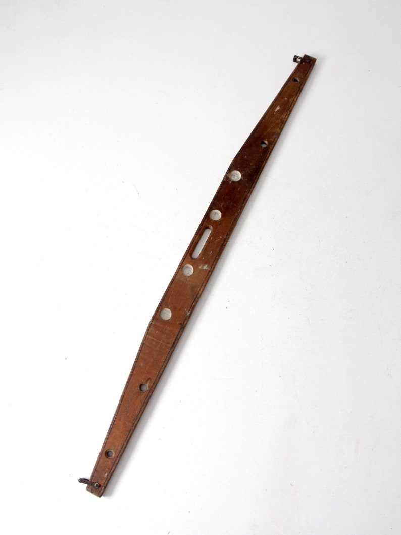 May include: A wooden level with metal brackets at each end. The level has several holes along its length.