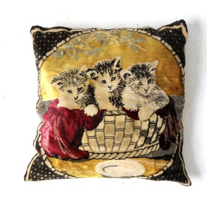 May include: A vintage velvet pillow with a gold background and a black border. Three kittens are depicted in a basket with a plate in front of them.