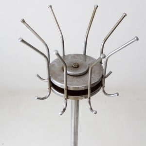 May include: A silver metal coat rack with a round base and multiple hooks. The hooks are arranged in a circular pattern around the base.