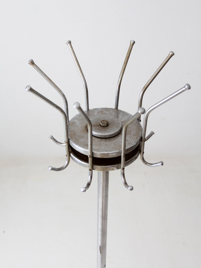 May include: A silver metal coat rack with a round base and multiple hooks. The hooks are arranged in a circular pattern around the base.