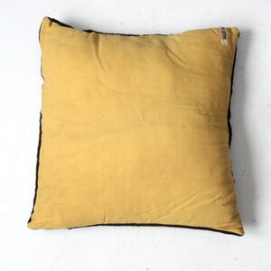 May include: A yellow throw pillow with a black border. The pillow has a small white label with the text "MADE IN INDIA" on the top right corner.