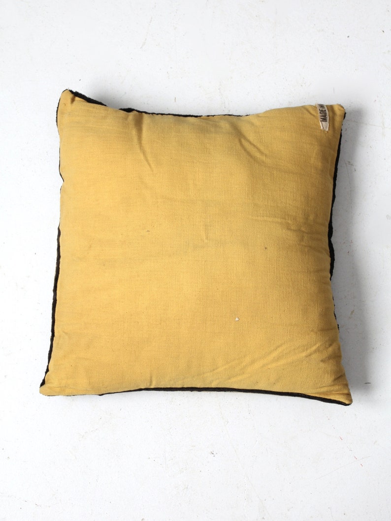 May include: A yellow throw pillow with a black border. The pillow has a small white label with the text "MADE IN INDIA" on the top right corner.