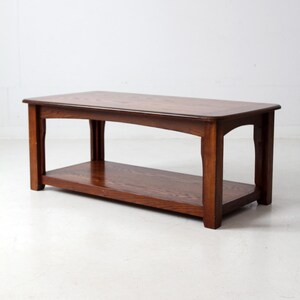 May include: A rectangular, dark brown wooden coffee table with a lower shelf. The table has a classic design with curved legs and a smooth, polished surface. The table is approximately 48 inches long, 24 inches wide, and 18 inches high.