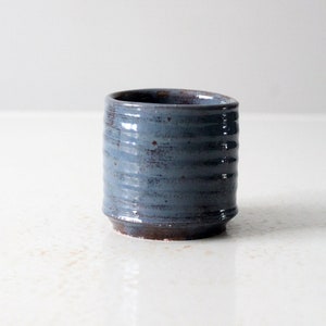 Peut inclure: Une tasse à thé en céramique bleue avec un bord brun et un motif texturé et côtelé.