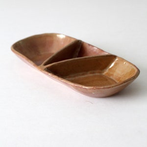 Op de afbeelding: Een bruine keramische schaal met drie verdeelde secties. De schaal is ovaalvormig en heeft een licht getextureerd oppervlak.