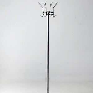 May include: A chrome coat rack with a circular base and multiple hooks. The rack is standing on a white surface.