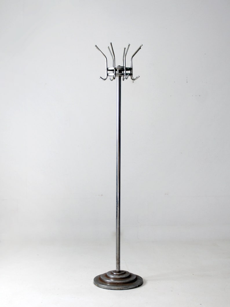 May include: A chrome coat rack with a circular base and multiple hooks. The rack is standing on a white surface.