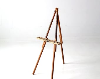 May include: A wooden easel with a simple design, perfect for displaying artwork or photos. The easel is made of natural wood and has a rustic look.