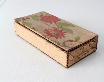 May include: A rectangular wooden box with a floral design on the lid. The box is made of light wood with a brown stain and has a decorative border around the edges. The floral design features red flowers and green leaves on a cream background.