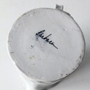 May include: White ceramic pitcher with a blue and white floral design. The bottom of the pitcher is marked with the word "Bluebell".