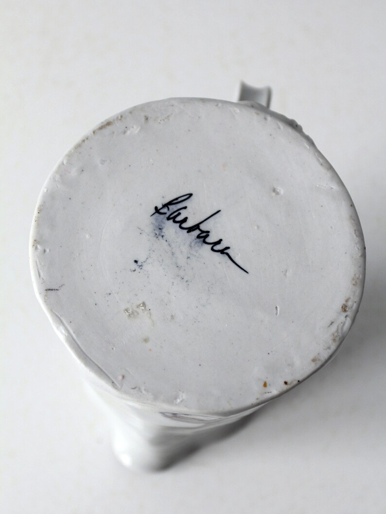 May include: White ceramic pitcher with a blue and white floral design. The bottom of the pitcher is marked with the word "Bluebell".