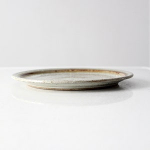 May include: A white ceramic plate with a brown rim. The plate has a slightly textured surface.
