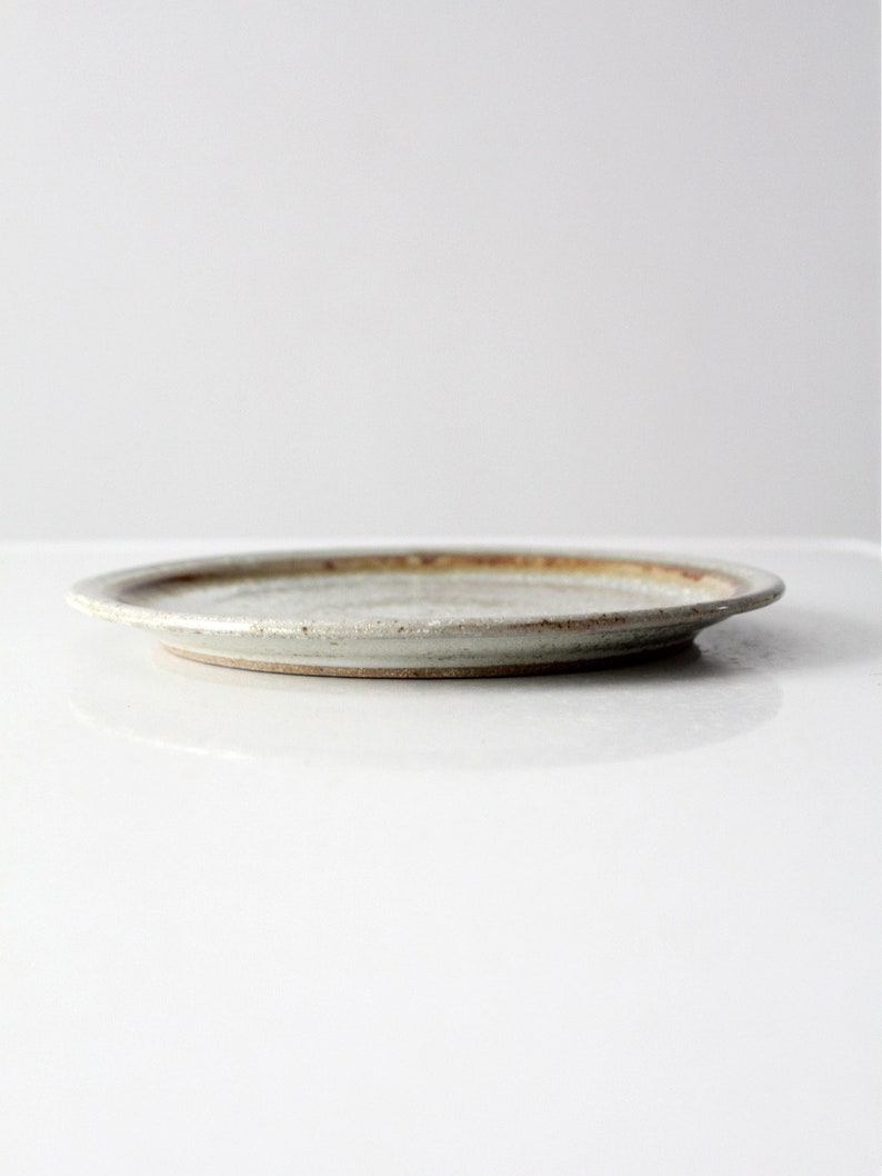 May include: A white ceramic plate with a brown rim. The plate has a slightly textured surface.