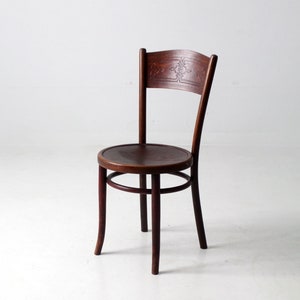 May include: A dark brown wooden chair with a carved back and a round seat. The chair has a simple design with four legs and a curved back.