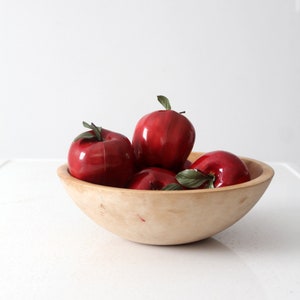 May include: A wooden bowl filled with red apples. The bowl is made of natural wood and has a rustic look. The apples are arranged in a cluster, with some of them overlapping.