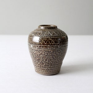 May include: A small, brown ceramic vase with a speckled glaze and a white, geometric design around the rim.