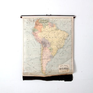 May include: A vintage map of South America, printed on paper and mounted on a roller. The map is titled "Ideal Series South America" and shows the countries of South America in different colors.