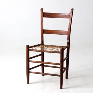 May include: A wooden chair with a woven seat and a simple, sturdy design. The chair is made of dark brown wood and has a natural finish.
