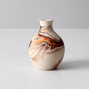 Könnte beinhalten: Eine kleine, runde Keramikvase mit einem Marmormuster in Braun-, Orange- und Weißtönen.