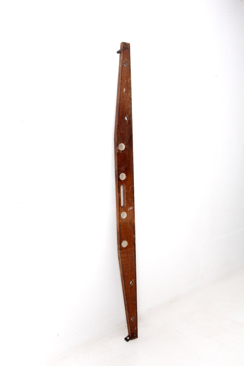 May include: A long, wooden level with five circular bubble levels. The level is brown and has a slight curve to it.
