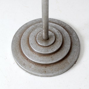 May include: A silver metal floor lamp base with a circular design. The base has concentric circles that create a layered effect.