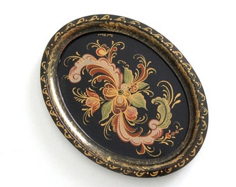 Op de afbeelding: Een ovale houten dienblad met een zwarte achtergrond en gouden rand. Het dienblad is versierd met een handgeschilderd bloemenontwerp in tinten rood, oranje, geel, groen en wit.