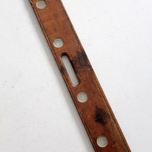 May include: A vintage wooden level with four glass vials. The level is brown and has a worn finish.