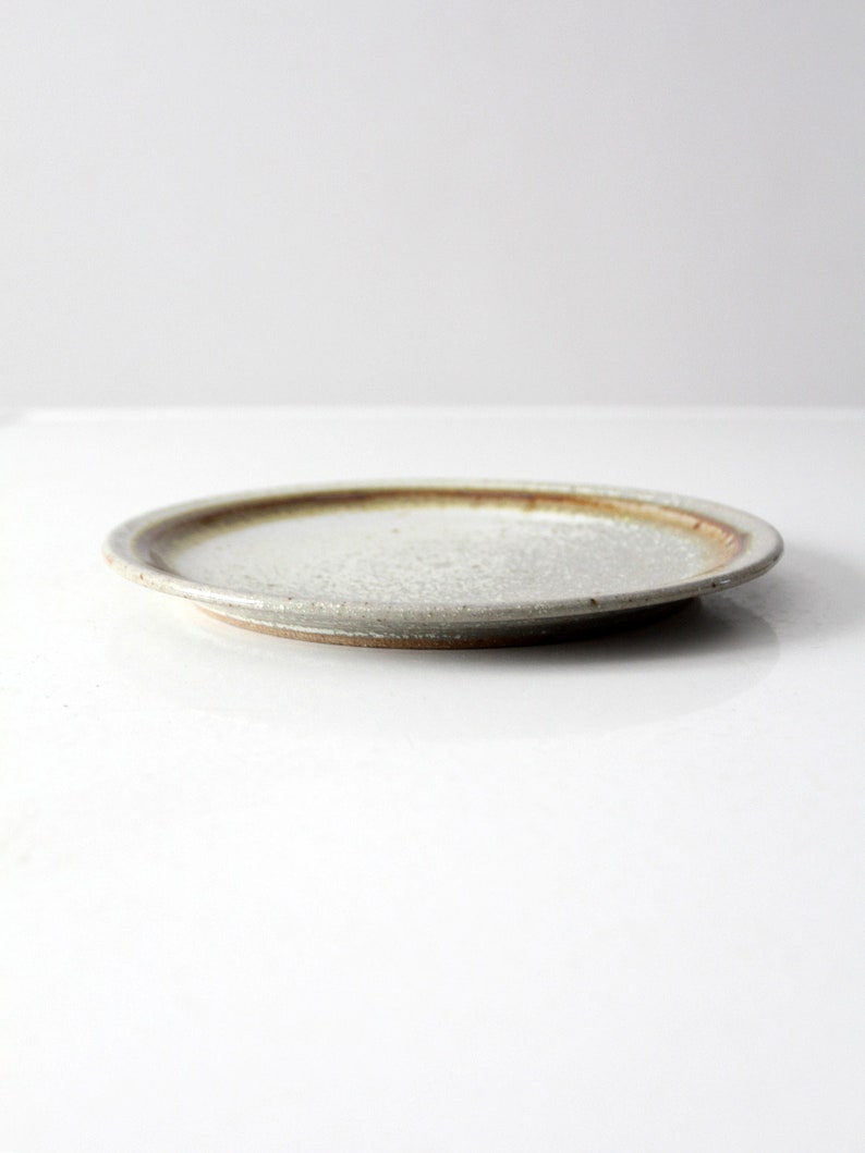 May include: A white ceramic plate with a brown rim. The plate has a slightly textured surface.