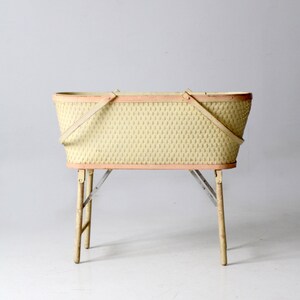 May include: A vintage wicker basket with a pink trim and wooden legs. The basket is empty and has two handles.
